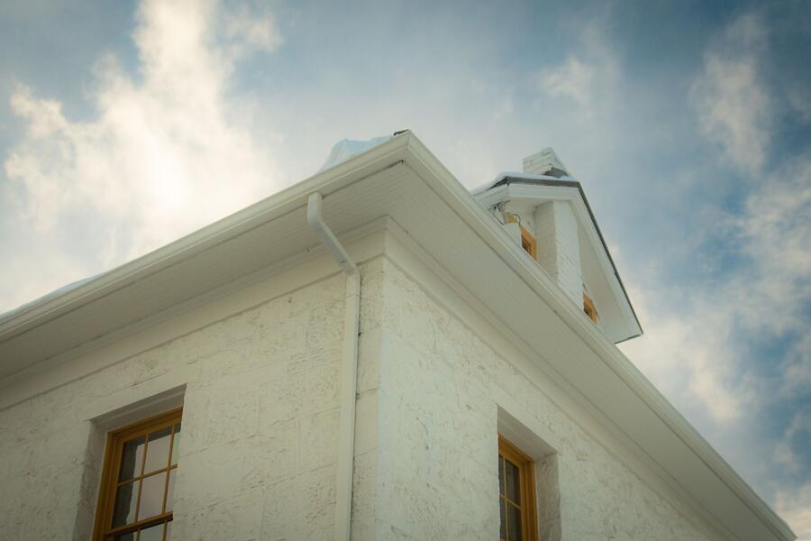 The underside of an older soffit and fascia against the sky