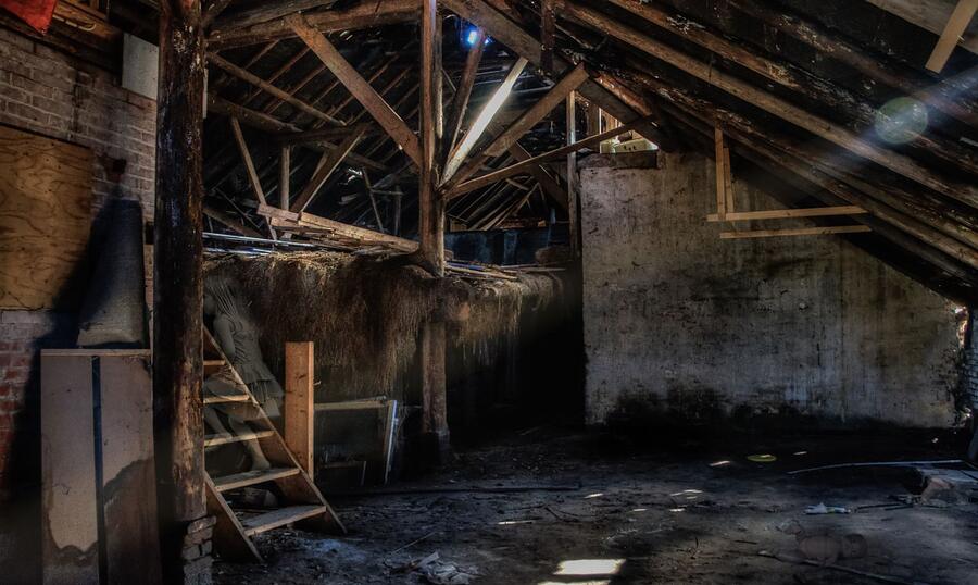 A sunlit attic with exposed wooden beams cleared and ready for new insulation