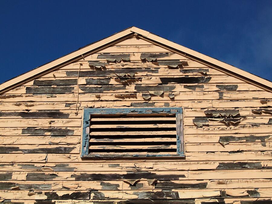 A louvered gable vent high on the end wall of an older house