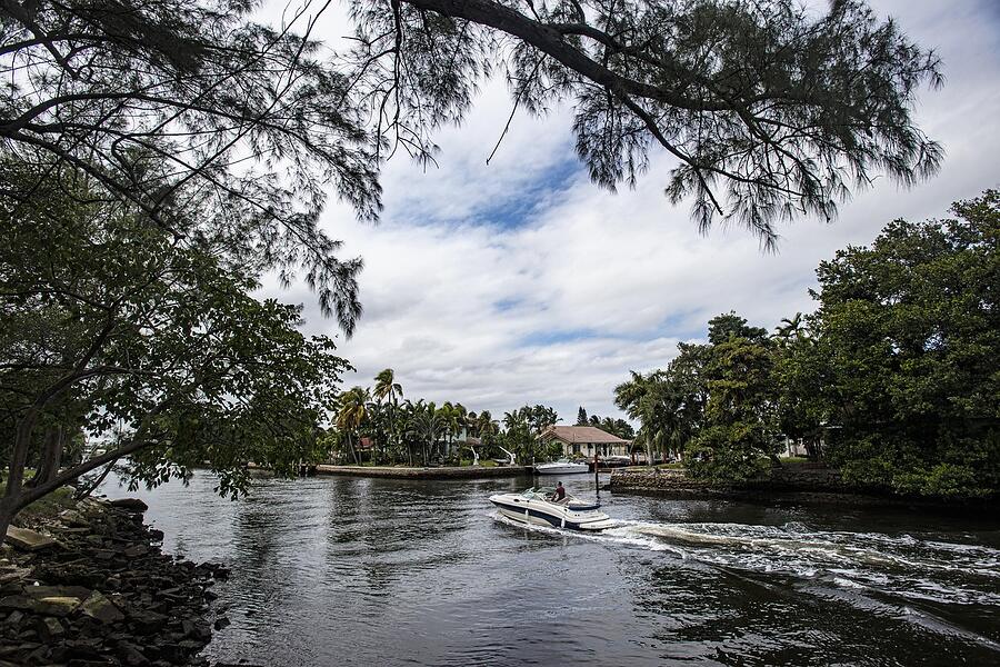 A boat moving along a tree-lined river in Fort Lauderdale