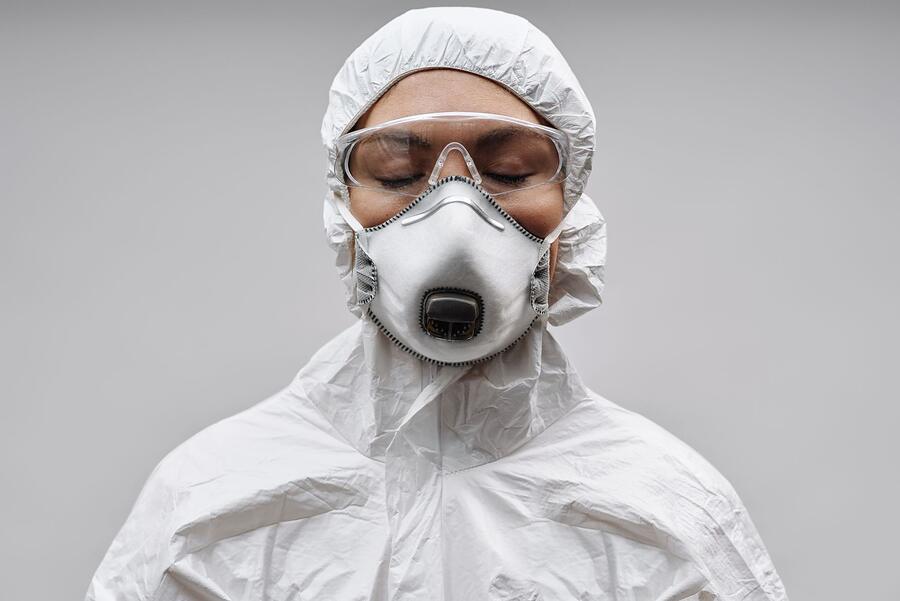 A person in a white protective suit and half-face respirator, seen from the side