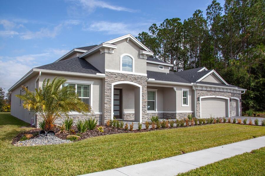 A single-story stucco house with a lawn and a shingle roof