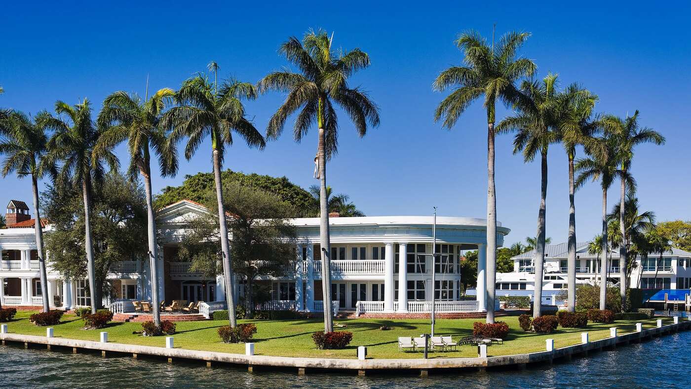 A large waterfront house with a barrel tile roof beside a canal